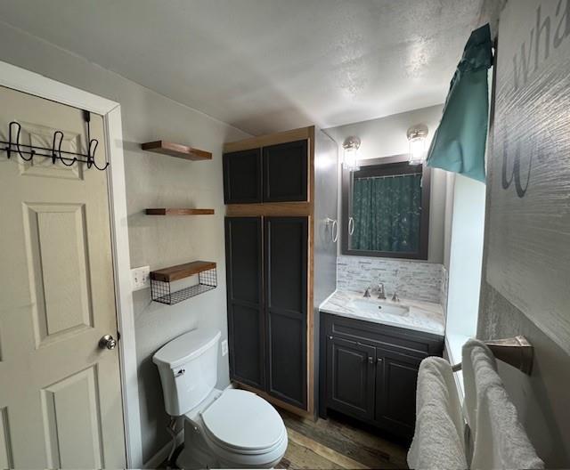 bathroom with backsplash, toilet, and vanity