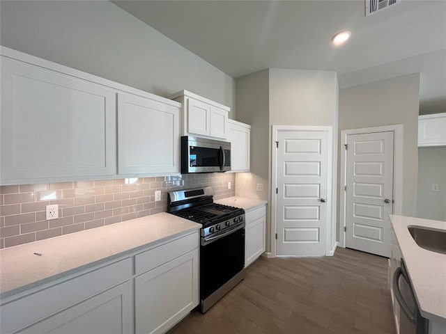 kitchen with white cabinetry, stainless steel appliances, tasteful backsplash, light stone counters, and light hardwood / wood-style flooring