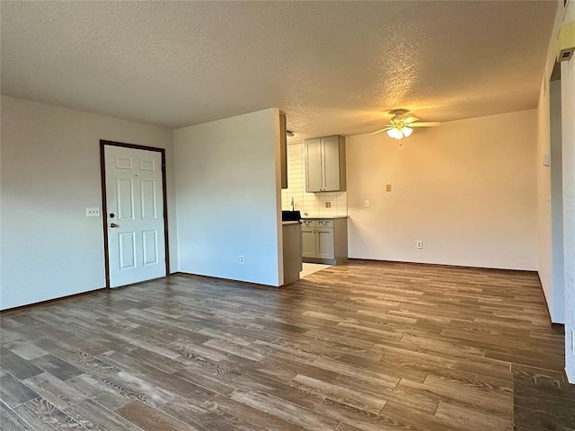 unfurnished living room featuring a textured ceiling, ceiling fan, and dark hardwood / wood-style floors