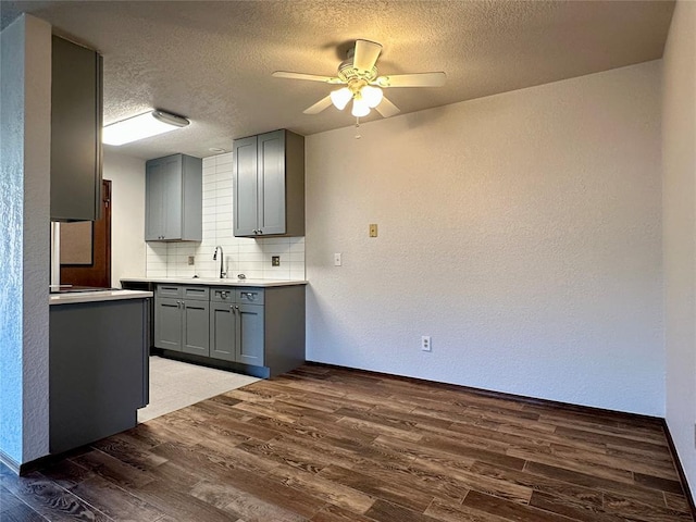 kitchen featuring backsplash, dark wood-type flooring, and gray cabinetry