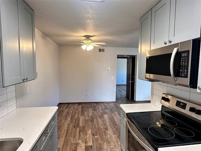 kitchen featuring ceiling fan, backsplash, stainless steel appliances, and a textured ceiling