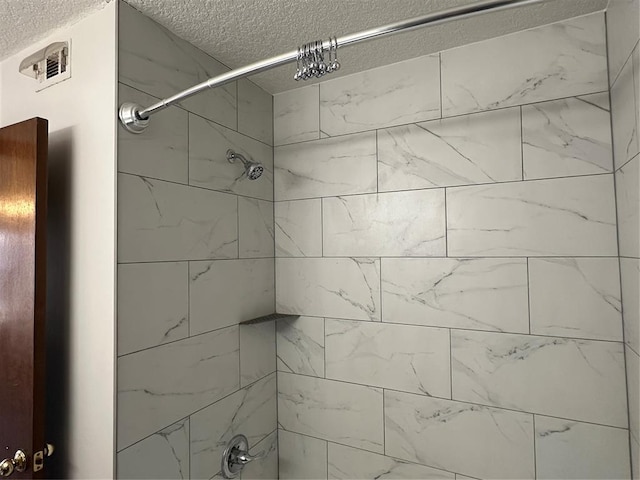 bathroom with a textured ceiling and tiled shower / bath