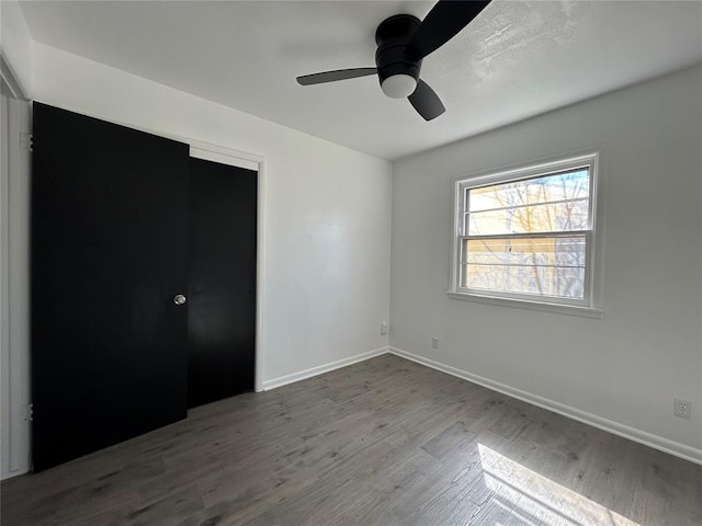 unfurnished bedroom with ceiling fan, a closet, baseboards, and wood finished floors