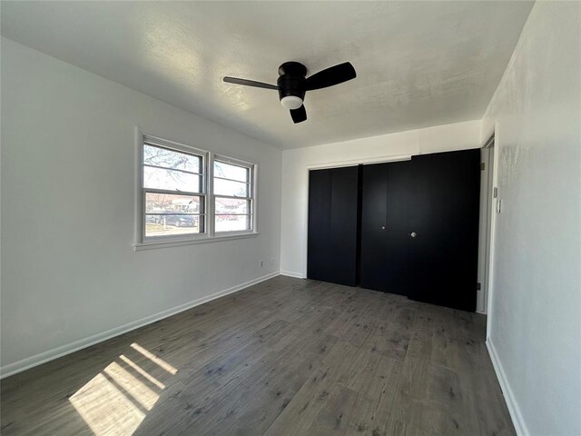 unfurnished bedroom with a closet, ceiling fan, baseboards, and wood finished floors