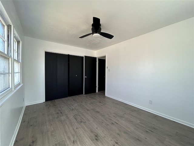 unfurnished bedroom featuring ceiling fan, a closet, wood finished floors, and baseboards