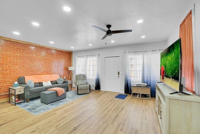 living room with ceiling fan, brick wall, and light hardwood / wood-style flooring