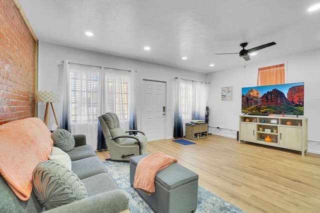 living room with ceiling fan, brick wall, and hardwood / wood-style floors