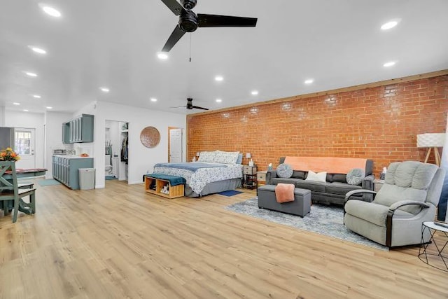 bedroom with ceiling fan, brick wall, and light hardwood / wood-style floors