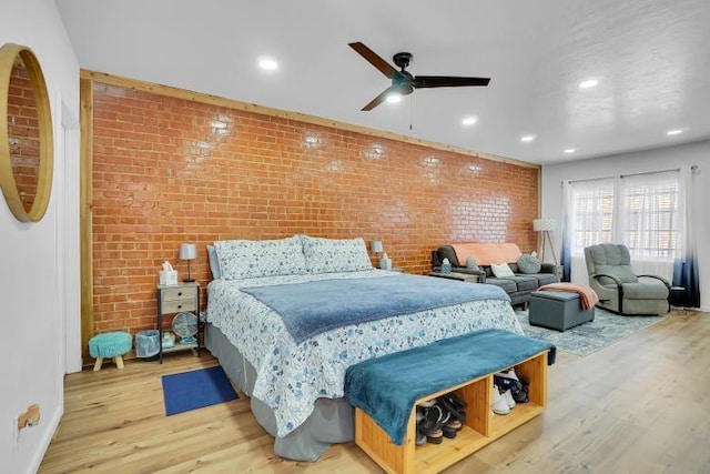 bedroom featuring ceiling fan, brick wall, and wood-type flooring