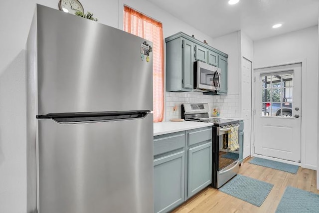 kitchen with light wood-type flooring, backsplash, and appliances with stainless steel finishes