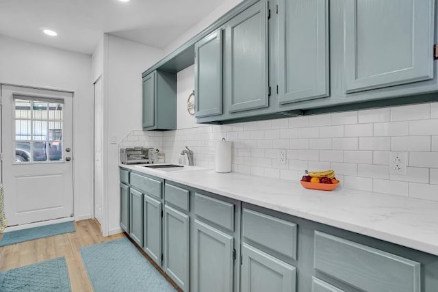 kitchen featuring light stone countertops, sink, tasteful backsplash, and light wood-type flooring