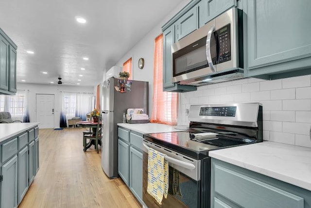 kitchen with ceiling fan, decorative backsplash, stainless steel appliances, and light hardwood / wood-style floors