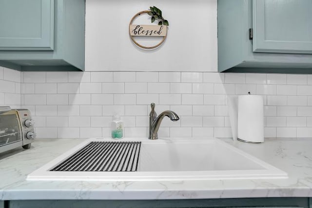 details featuring decorative backsplash, light stone countertops, and sink