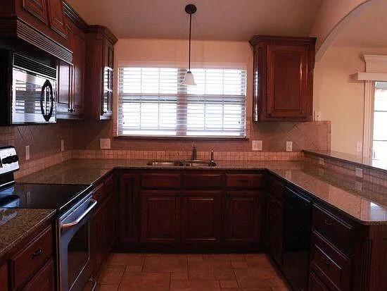 kitchen with decorative light fixtures, sink, dark stone countertops, backsplash, and stainless steel appliances