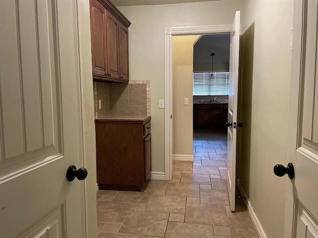 laundry area with stone finish floor, a sink, and baseboards