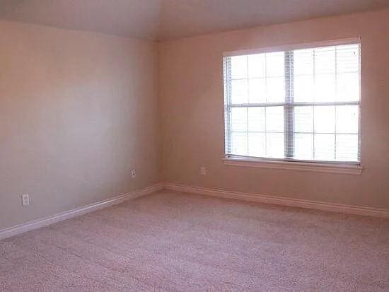 empty room featuring light carpet and baseboards