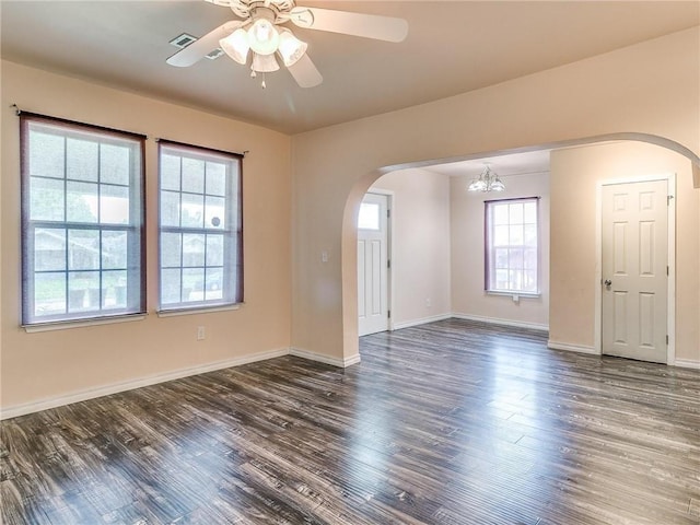 unfurnished room with ceiling fan with notable chandelier and dark hardwood / wood-style flooring