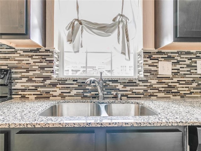 kitchen featuring decorative backsplash, sink, and light stone counters