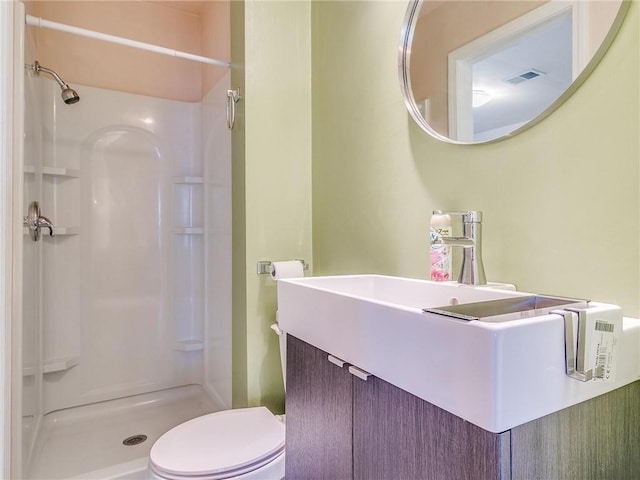 bathroom with toilet, vanity, and a shower