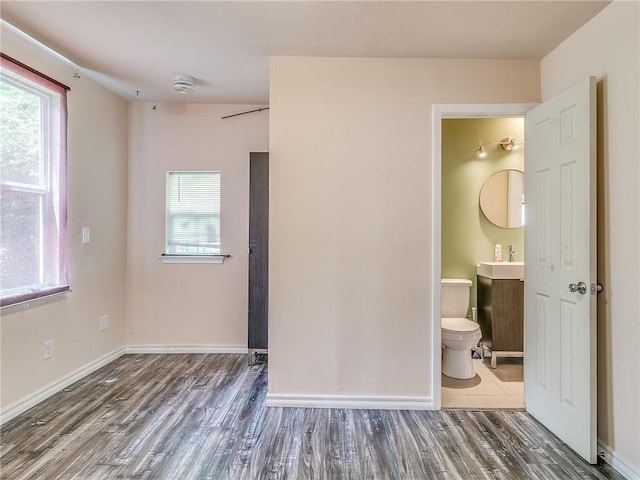 unfurnished bedroom with ensuite bathroom, sink, and dark hardwood / wood-style floors