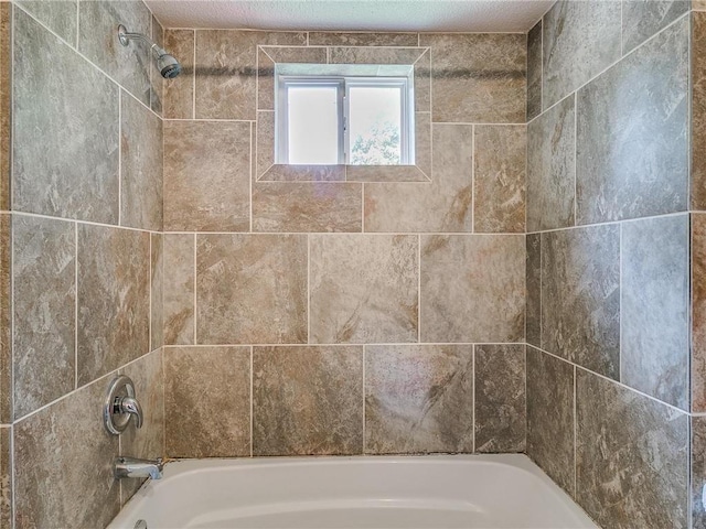 bathroom with tiled shower / bath combo and a textured ceiling