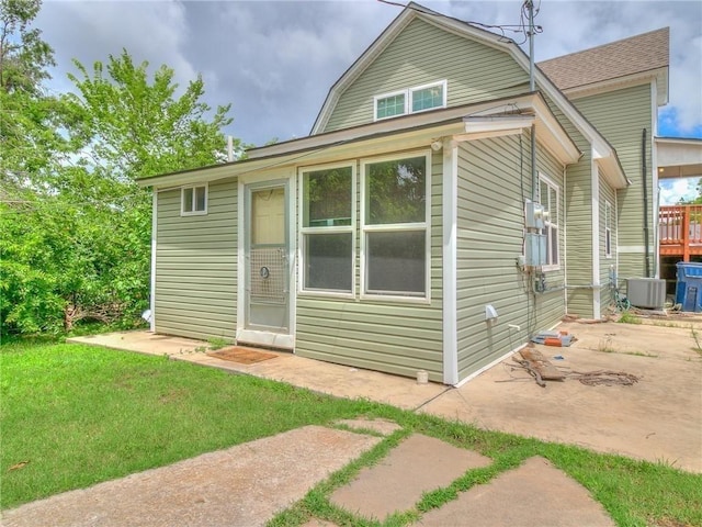 back of property with central air condition unit, a lawn, and a patio area