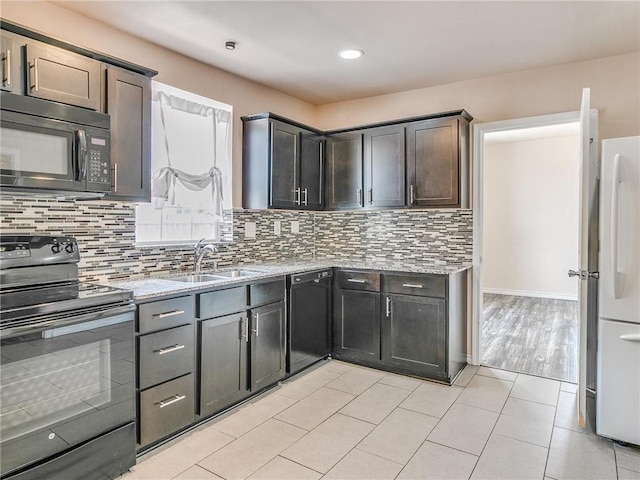 kitchen with light stone counters, black appliances, decorative backsplash, light tile patterned floors, and sink