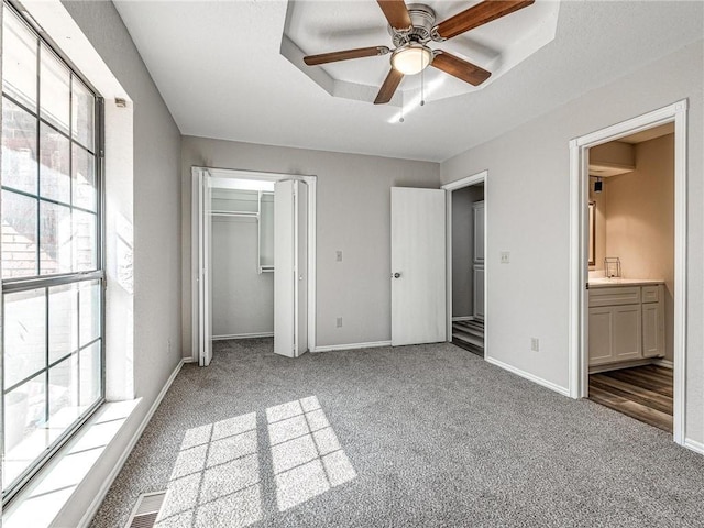 unfurnished bedroom featuring ceiling fan, light colored carpet, connected bathroom, and a closet