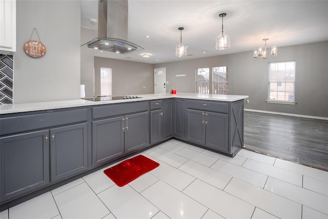 kitchen with decorative light fixtures, kitchen peninsula, gray cabinetry, island range hood, and black electric cooktop