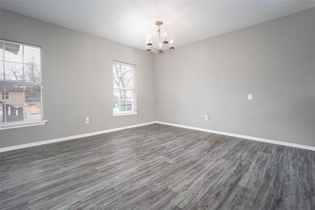 empty room with dark wood-type flooring and a chandelier