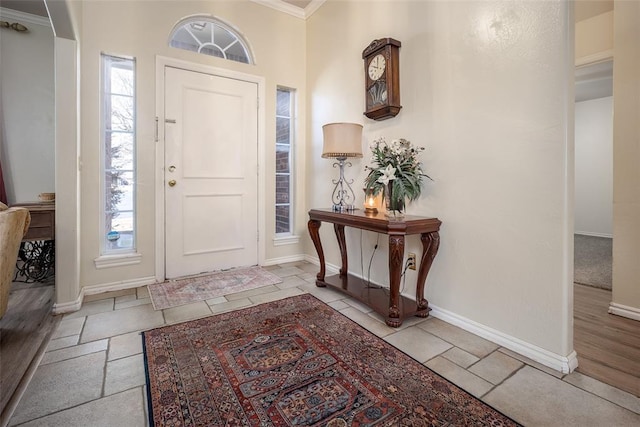 entrance foyer featuring crown molding, baseboards, and stone tile floors