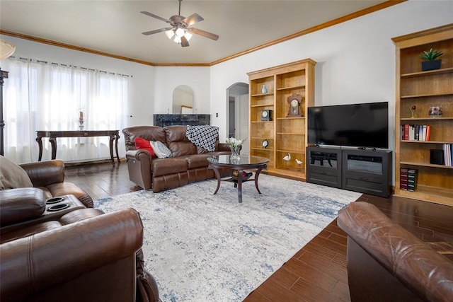 living room featuring ceiling fan, ornamental molding, arched walkways, and dark wood-style flooring