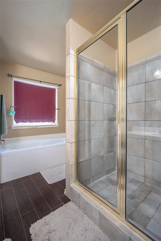 full bathroom featuring wood finish floors, a shower stall, and a bath