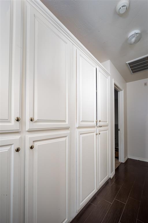 hall with baseboards, visible vents, and wood finish floors