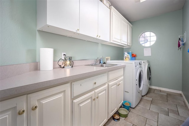 clothes washing area with separate washer and dryer, a sink, cabinet space, and baseboards