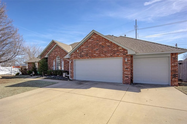 view of front facade with brick siding, driveway, and roof with shingles