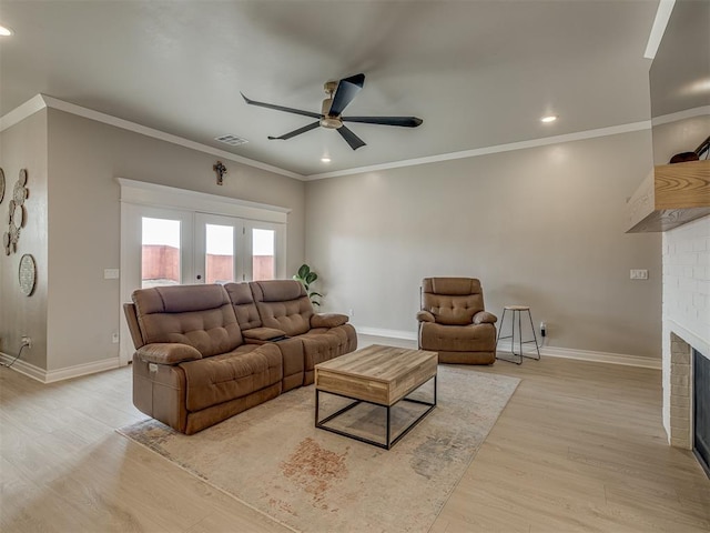 living room with ceiling fan, ornamental molding, light hardwood / wood-style floors, and a fireplace