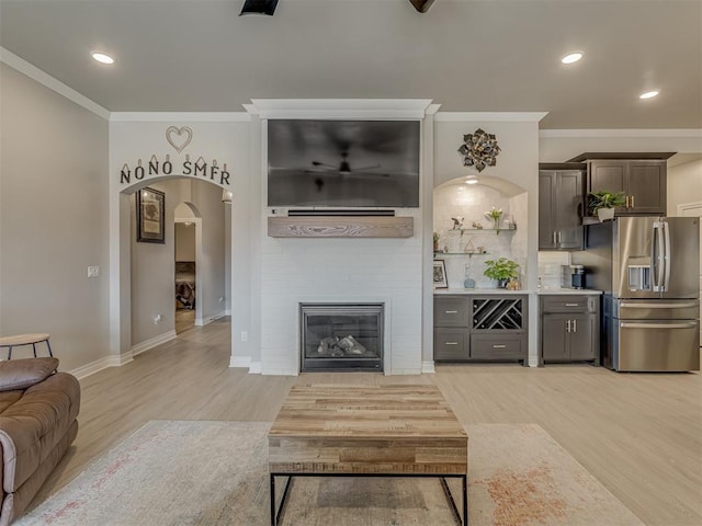 living room with light wood-type flooring, a fireplace, and ornamental molding