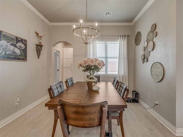 dining space featuring ornamental molding, a notable chandelier, and light wood-type flooring