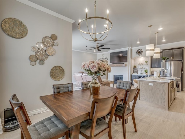 dining room with light wood-type flooring, ceiling fan with notable chandelier, and ornamental molding