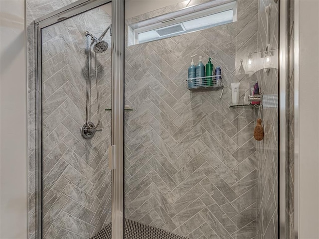 bathroom featuring a shower with shower door and a wealth of natural light