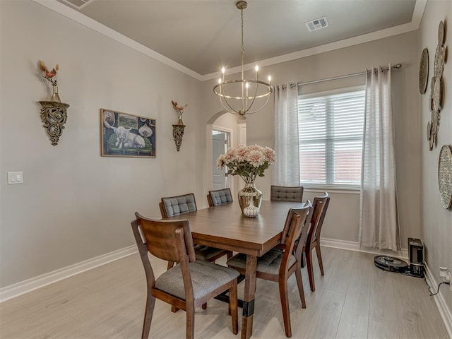 9312 Taggert Ln, Yukon, OK 73099 - dining space featuring light wood-style floors, arched walkways, a chandelier, baseboards, and ornamental molding