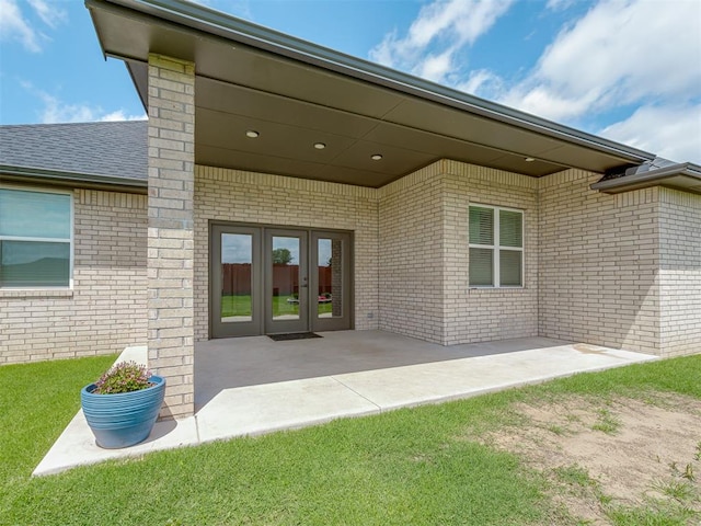 9312 Taggert Ln, Yukon, OK 73099 - property entrance featuring french doors, brick siding, a patio, and a lawn