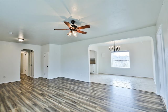 empty room with ceiling fan with notable chandelier and wood-type flooring