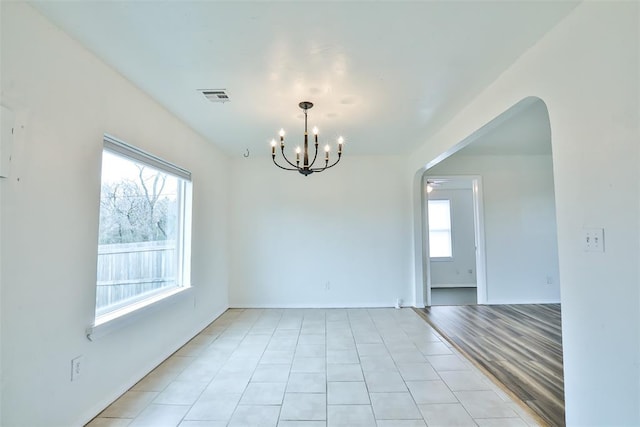 unfurnished room featuring light tile patterned floors and a notable chandelier