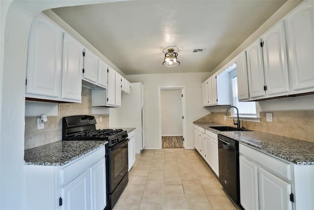 kitchen with black appliances, sink, light tile patterned flooring, white cabinets, and dark stone counters