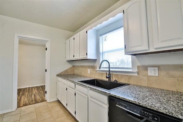 kitchen featuring backsplash, sink, light tile patterned floors, black dishwasher, and white cabinets