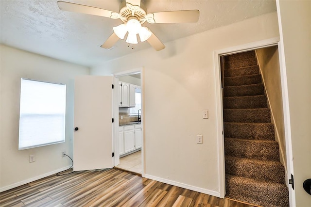 staircase featuring ceiling fan, sink, and hardwood / wood-style flooring