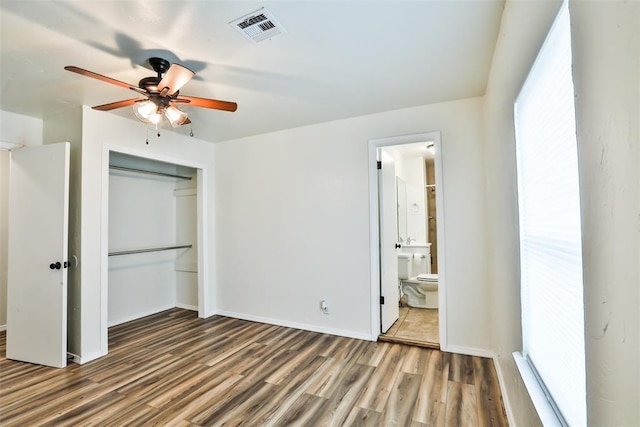 unfurnished bedroom with ceiling fan, connected bathroom, wood-type flooring, and a closet