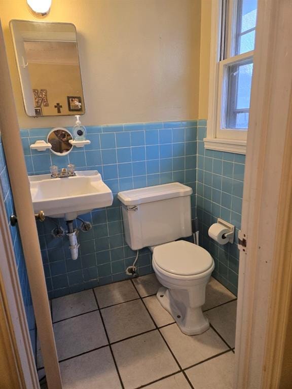 bathroom with toilet, tile patterned flooring, tile walls, and sink